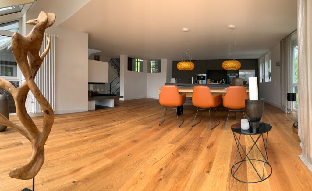 großzügiges Esszimmer mit neuem Holzbodenbelag sorgt in Kombination mit den ledernen Stühlen und den orangenen Pendelleuchten für eine Wohlfühlatmosphäre